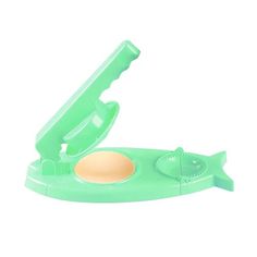 a green plastic object with a hole in the middle and an egg inside it on a white background