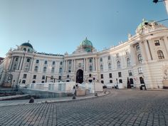 a large white building sitting on top of a cobblestone street