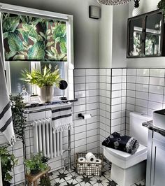 a white toilet sitting next to a window in a bathroom with black and white tiles