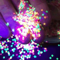 a person's hand with purple and green stars on it