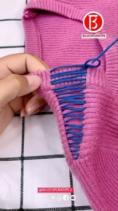 someone is stitching the blue thread on a pink sweater