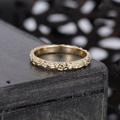 a gold wedding ring sitting on top of a wooden table