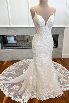 a white wedding dress on display in front of a fireplace with an open - back