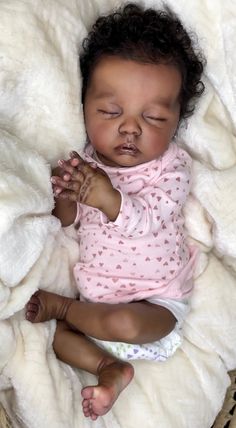 a baby is laying down on a blanket with its eyes closed and hands clasped to her chest