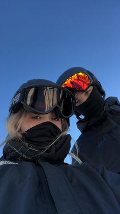 two people wearing ski goggles and black jackets