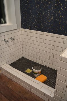 a bucket of paint sitting on top of a wooden floor next to a tub in a bathroom