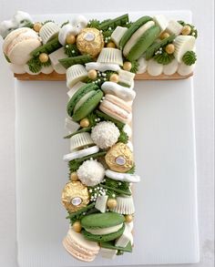 a letter made out of food on top of a white plate with green and gold decorations