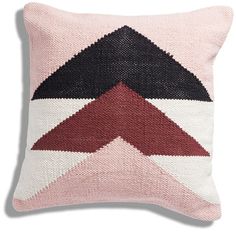 a pink pillow with black, red and white triangles on it's side in the shape of an arrow