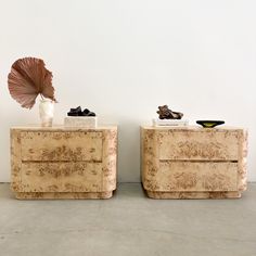 two side tables made out of marble with an umbrella on one end and a shell sculpture on the other