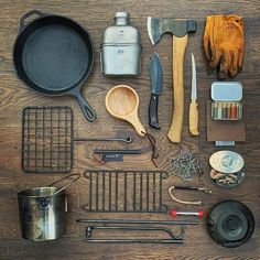 an assortment of kitchen utensils laid out on top of a wooden table next to pots and pans