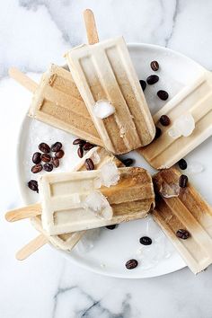 three popsicles with ice cream and chocolate chips on a white plate next to coffee beans