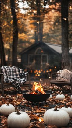 an outdoor fire pit surrounded by chairs and pumpkins