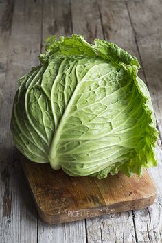 a head of lettuce sitting on top of a wooden cutting board