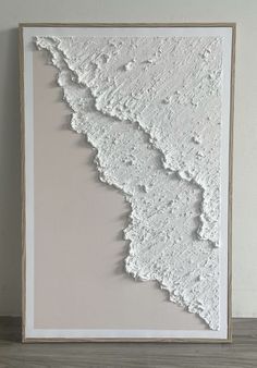 a large white paper cut in half on top of a wooden table next to a wall