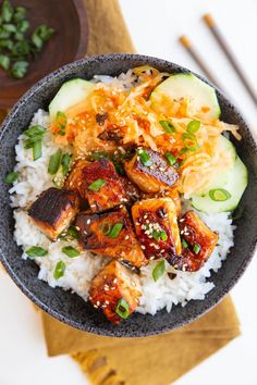 a bowl filled with rice, meat and veggies on top of a table