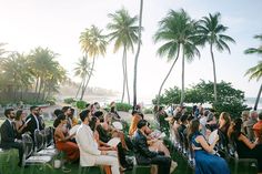 a group of people sitting on lawn chairs next to each other with palm trees in the background