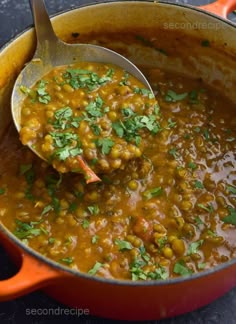 a ladle full of lentils and garnishes in a red pot