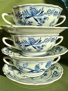 a stack of blue and white dishes sitting on top of a green cloth covered table