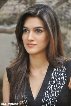 a woman with long brown hair wearing a black and white dress posing for the camera