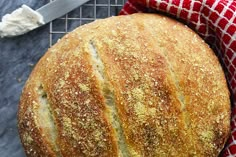 a loaf of bread sitting on top of a red and white towel next to a knife