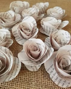 paper flowers made out of old book pages on a burlap tablecloth with words written all over them