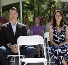 a man and woman sitting next to each other in front of a group of people