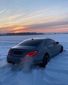 a car is driving through the snow with its brake lights on and it's exhaust coming out