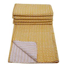 the yellow and white blanket is folded on top of each other, with two different patterns