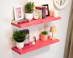 two pink shelves with books and plants on them