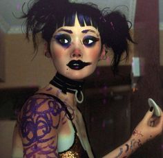 a woman with makeup and piercings holding a cell phone