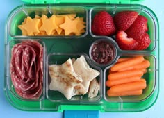 a plastic container filled with different types of food next to strawberries and carrots