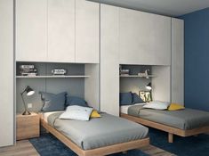 two beds in a room with blue carpeting and white cupboards on the walls