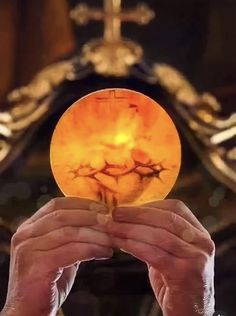 a person holding up a glass ball in front of a cross