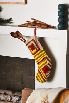 a christmas stocking hanging from a fireplace with wooden spoons on the mantle and stockings