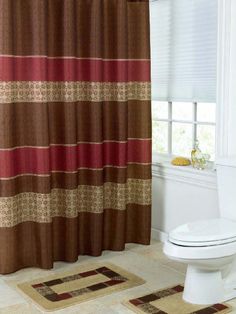 a bathroom with a toilet, shower curtain and rugs in front of the window