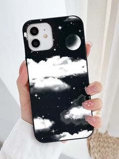 a woman is holding up her phone case with clouds and stars on the sky in the background