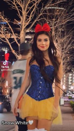 a woman in a snow white and yellow dress is standing on the street at night