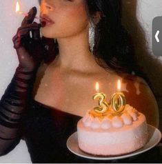 a woman blowing out candles on her birthday cake with the number twenty two in front of her