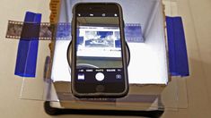 an iphone sitting on top of a glass table next to a box with blue tape