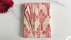 red and white napkins are folded on a marble surface with flowers in the background