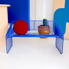 a blue shelf with two pots and a red ball on it in front of a white wall