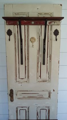 an old white door with brown handles and bars on the top, next to a wooden bench