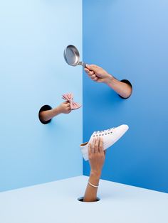 two hands reaching for a pair of shoes with one hand holding a frying pan