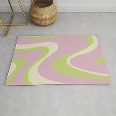 a pink, green and yellow rug on the floor next to a basket with a wicker basket