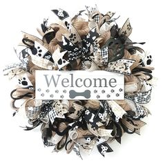 a welcome sign is displayed on a dog's deco mesh wreath with paw prints and bones