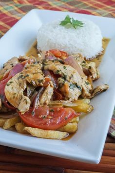 a white plate topped with chicken and veggies next to rice