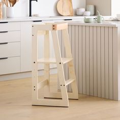 a wooden step stool sitting on top of a hard wood floor next to a kitchen counter