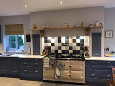 a kitchen with an oven, stove and counter tops in grey and white tiles on the walls