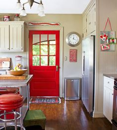 a kitchen with red door and stools in it