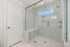 a walk in shower sitting inside of a bathroom next to a white door and window